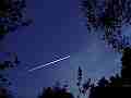 Single jet trail streaks through opening in trees � digitally upscaled timelapse scene from Stitching the Sky Cat.#V01058x, 1280x720 Motion JPEG (.AVI), 4 sec. at 30fps 